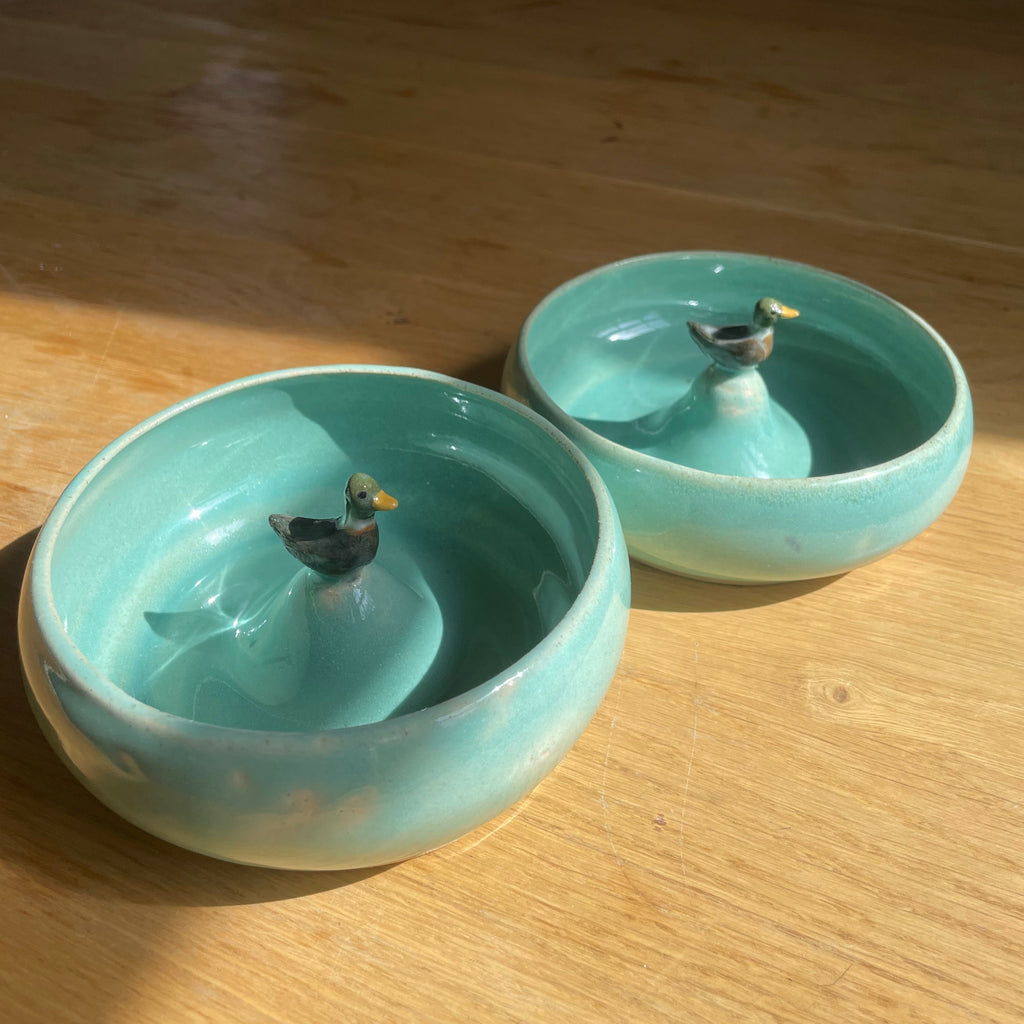 Two turquoise ceramic bowls on a wooden table