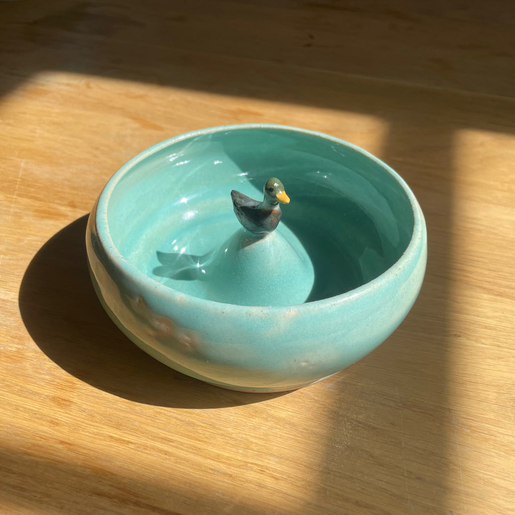 Turquoise ceramic bowl with a decorative bird